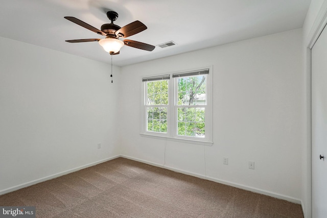carpeted spare room featuring ceiling fan, baseboards, and visible vents