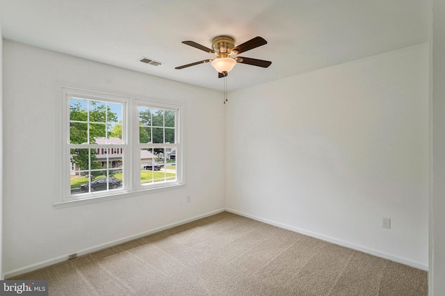 carpeted spare room featuring ceiling fan, baseboards, and visible vents