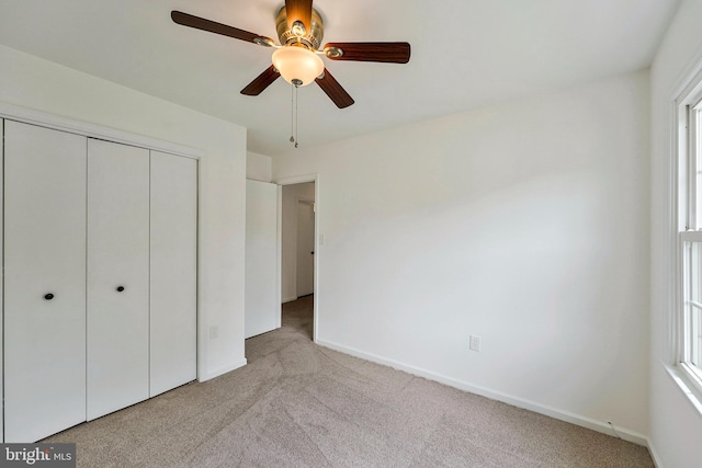 unfurnished bedroom featuring light colored carpet, a closet, and baseboards