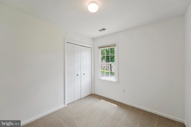 unfurnished bedroom with a closet, visible vents, baseboards, and light carpet