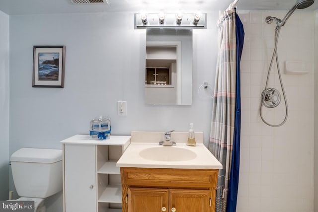 bathroom featuring vanity, toilet, tiled shower, and visible vents