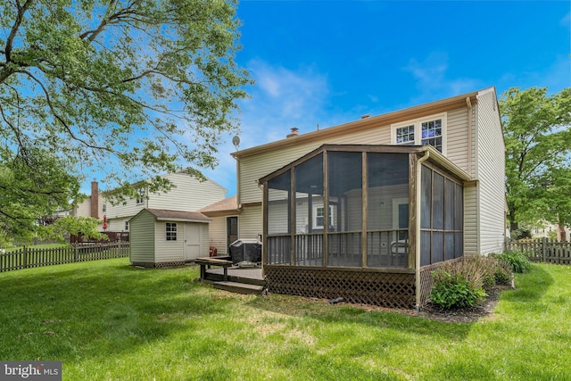 back of house with a storage unit, a sunroom, a yard, fence, and an outbuilding
