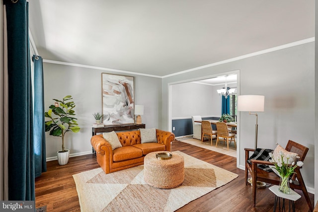 living room featuring a chandelier, ornamental molding, baseboards, and wood finished floors