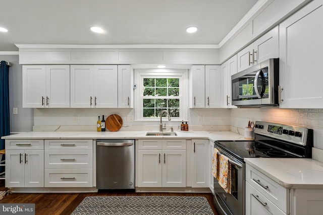 kitchen with a sink, ornamental molding, white cabinets, and appliances with stainless steel finishes