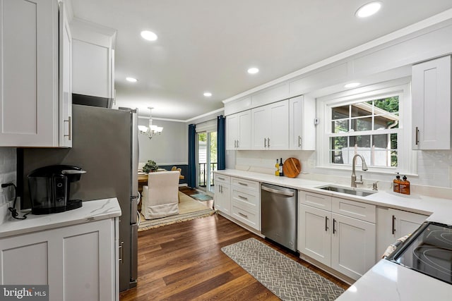kitchen with a sink, ornamental molding, an inviting chandelier, decorative backsplash, and appliances with stainless steel finishes