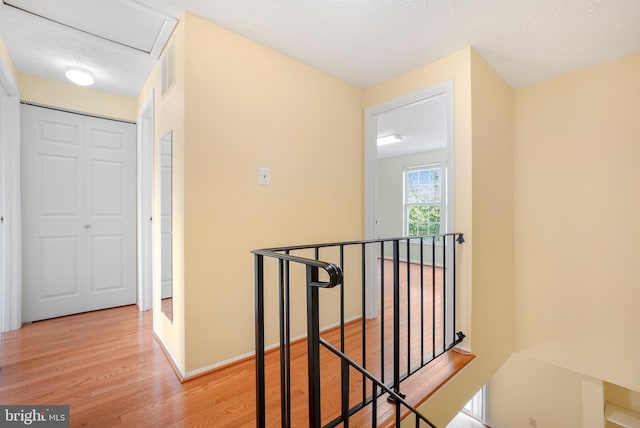 hall featuring light wood finished floors and an upstairs landing