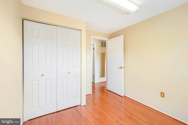 unfurnished bedroom featuring baseboards, a closet, light wood-type flooring, and visible vents