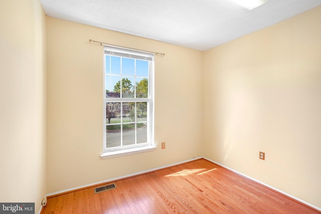 spare room with visible vents, baseboards, and hardwood / wood-style floors