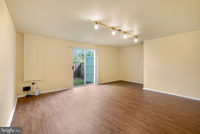 unfurnished room featuring baseboards, rail lighting, and wood finished floors