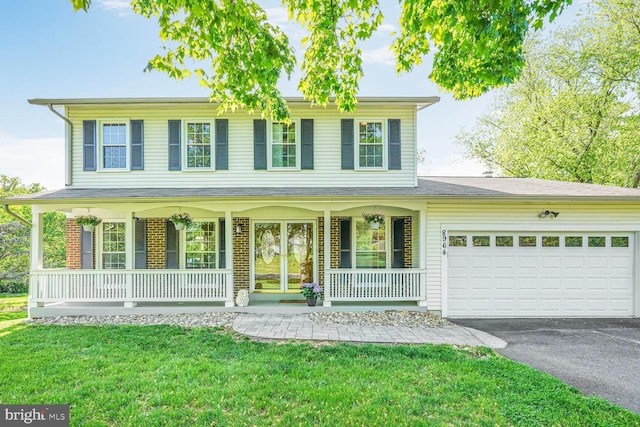 colonial house featuring a garage, aphalt driveway, a front yard, brick siding, and a porch