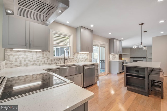 kitchen featuring a sink, ventilation hood, light wood finished floors, dishwasher, and gray cabinets