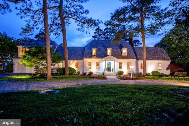 view of front of house with a chimney, a front lawn, curved driveway, and stucco siding