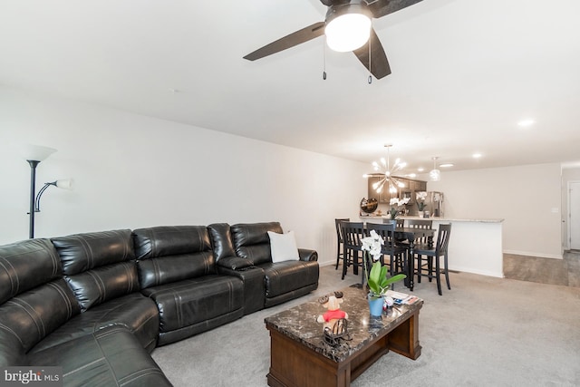 living room with baseboards, light carpet, and ceiling fan with notable chandelier