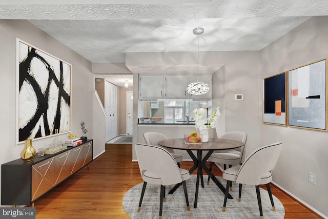 dining space with an inviting chandelier, wood finished floors, and baseboards