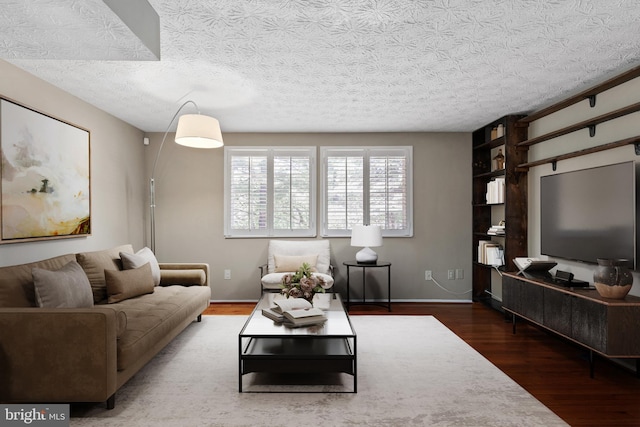 living area featuring a textured ceiling, wood finished floors, and baseboards