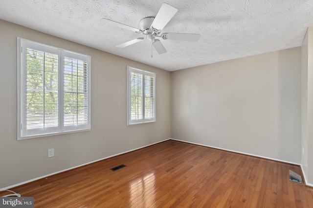 unfurnished room with wood finished floors, visible vents, a ceiling fan, and a textured ceiling