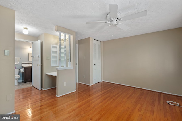 unfurnished bedroom with a textured ceiling, wood finished floors, and baseboards