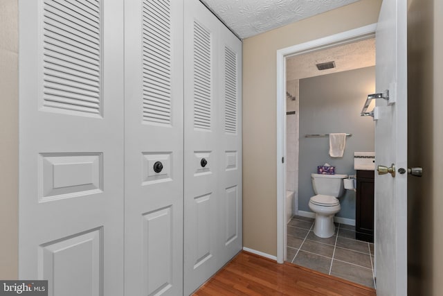 bathroom with visible vents, baseboards, a closet, toilet, and wood finished floors