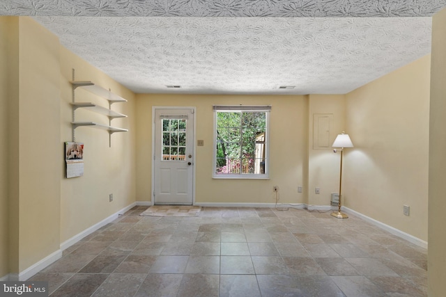 foyer with baseboards, visible vents, a textured ceiling, and stone finish floor