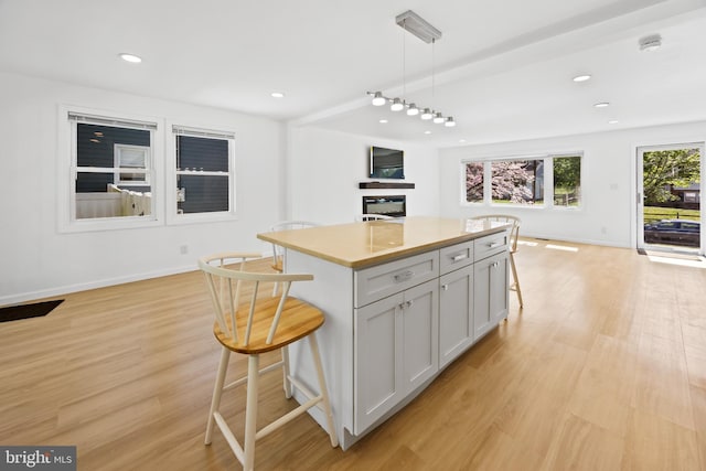 kitchen featuring a breakfast bar area, a kitchen island, light wood-type flooring, and open floor plan