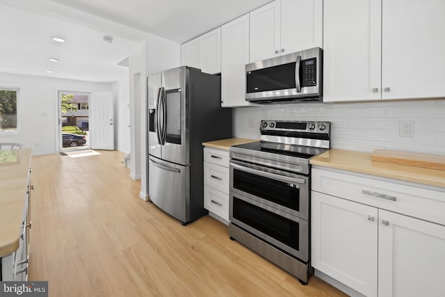 kitchen with recessed lighting, white cabinetry, light wood finished floors, appliances with stainless steel finishes, and backsplash