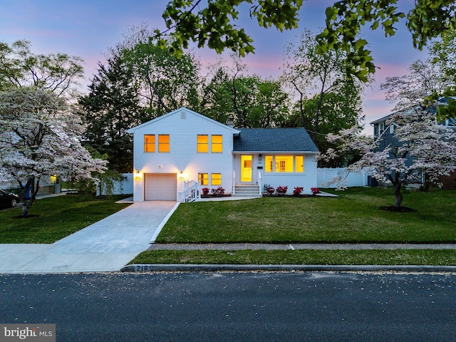 tri-level home featuring fence, an attached garage, a yard, and driveway