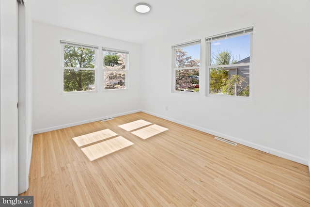 spare room with baseboards, wood finished floors, and visible vents
