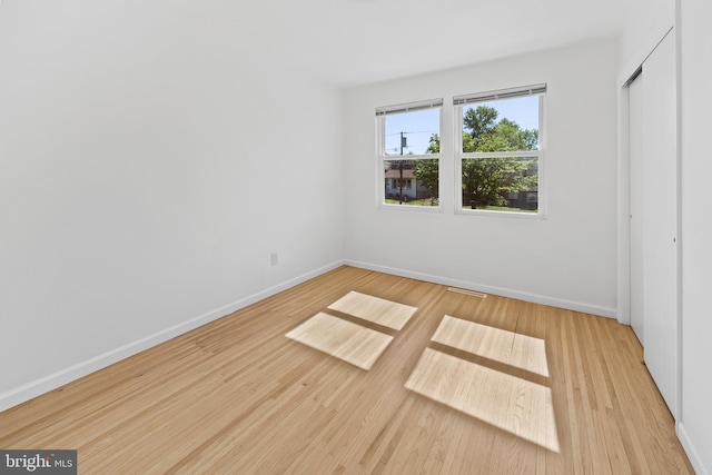 unfurnished bedroom featuring baseboards, wood finished floors, and a closet