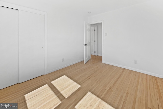 unfurnished bedroom with baseboards, a closet, and wood finished floors