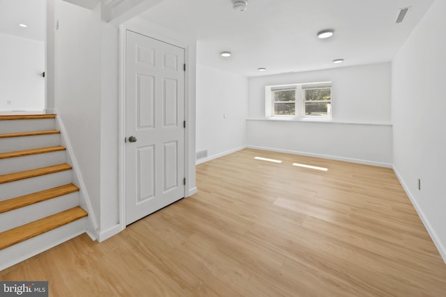 interior space with light wood-style floors, baseboards, stairway, and visible vents