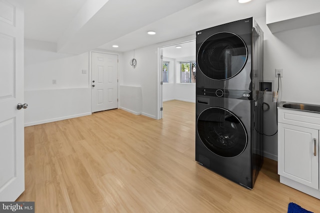 washroom featuring stacked washing maching and dryer, baseboards, light wood-style floors, and recessed lighting