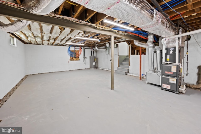 unfinished below grade area with heating unit, stairs, concrete block wall, and electric water heater