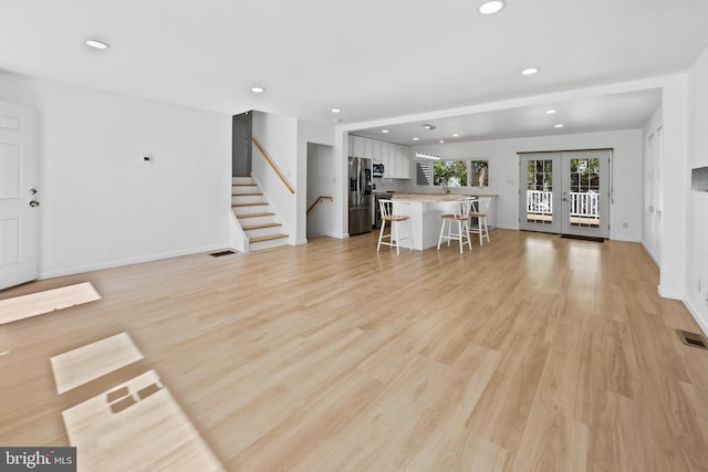 living room featuring recessed lighting, stairs, light wood-style floors, and french doors