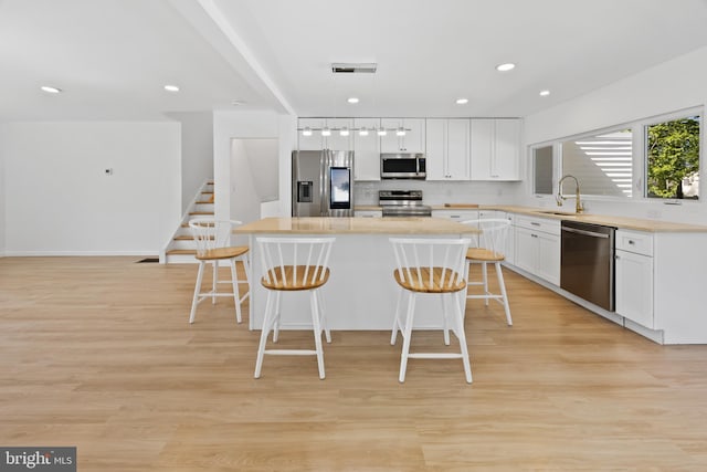 kitchen with a kitchen island, a breakfast bar, a sink, backsplash, and stainless steel appliances
