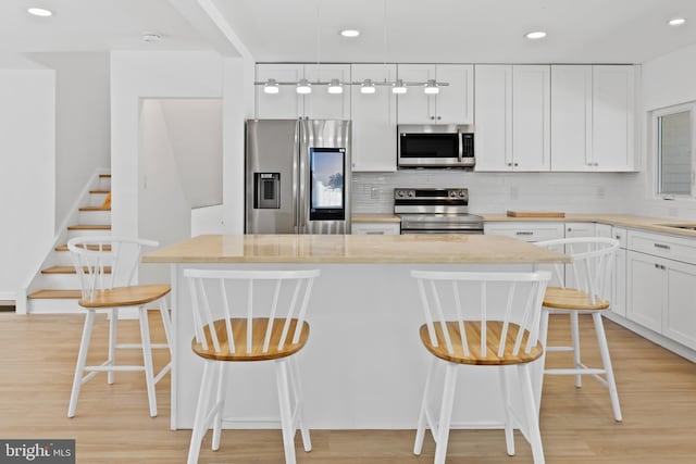 kitchen featuring recessed lighting, appliances with stainless steel finishes, a kitchen bar, and tasteful backsplash