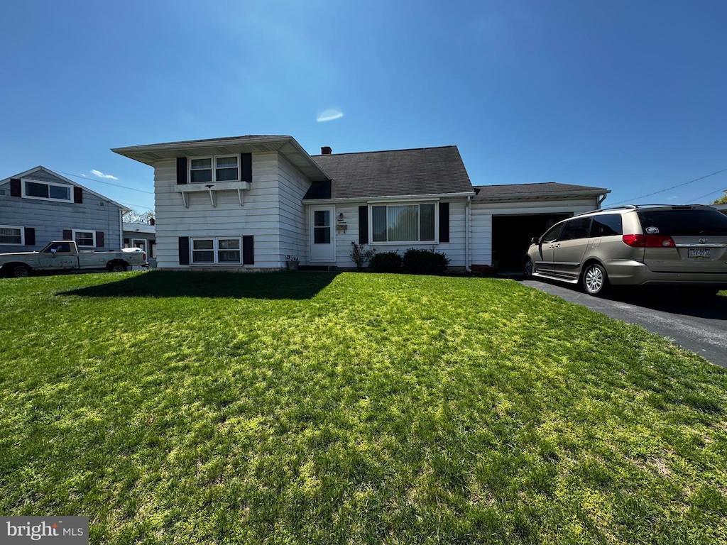 split level home featuring a garage, a front yard, and driveway