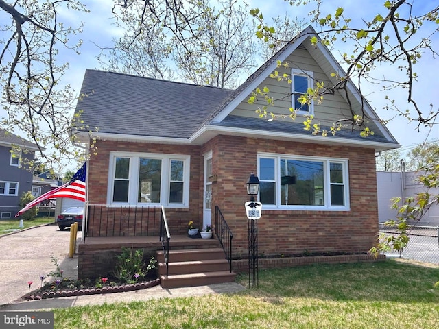 view of front of property with roof with shingles, fence, and brick siding