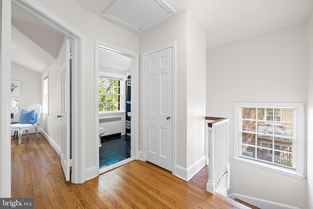 foyer entrance with radiator heating unit, baseboards, and light wood-type flooring