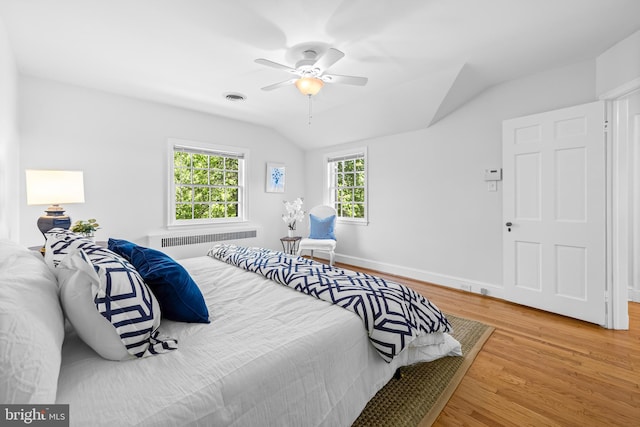 bedroom featuring visible vents, radiator, wood finished floors, a ceiling fan, and vaulted ceiling