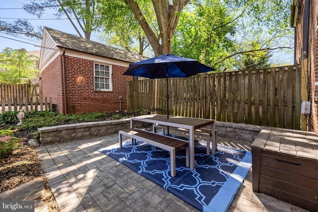 view of patio / terrace featuring outdoor dining area, a fenced backyard, and an outdoor structure