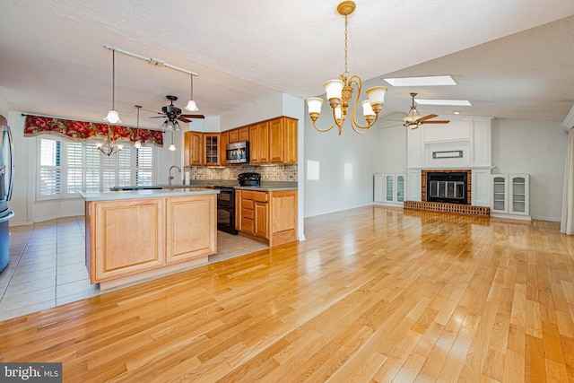 kitchen featuring stainless steel appliances, ceiling fan, a chandelier, light wood-style flooring, and a textured ceiling