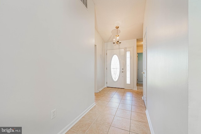 foyer entrance with a chandelier, light tile patterned flooring, and baseboards