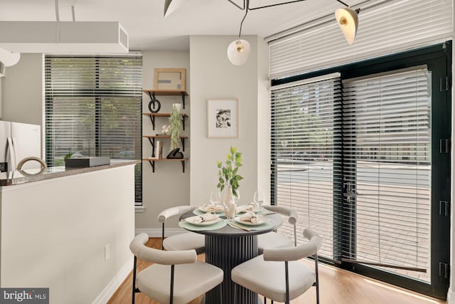dining area with baseboards, plenty of natural light, and wood finished floors