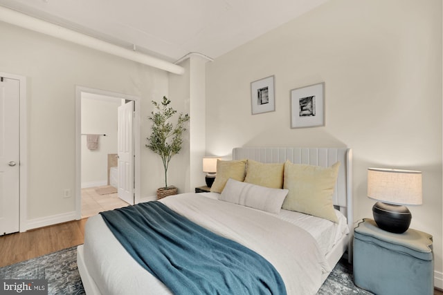 bedroom featuring ensuite bathroom, baseboards, and wood finished floors