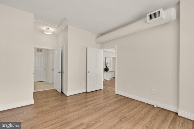 unfurnished room with baseboards, light wood-type flooring, and visible vents