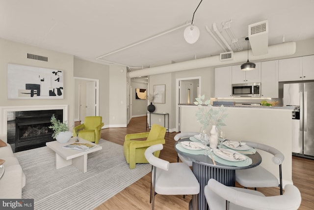 dining area with visible vents, attic access, and wood finished floors