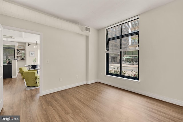 spare room with baseboards and wood finished floors