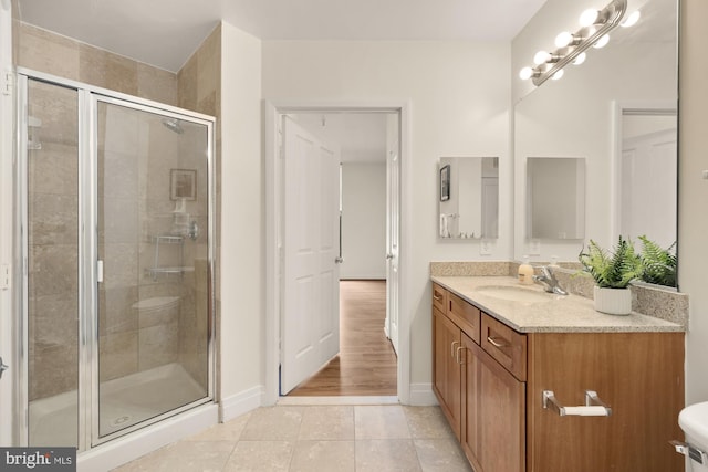 full bath with vanity, tile patterned floors, baseboards, and a stall shower