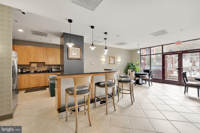 kitchen with a kitchen breakfast bar, french doors, dark countertops, tasteful backsplash, and light tile patterned flooring