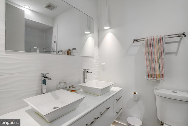 bathroom with a sink, toilet, double vanity, and visible vents